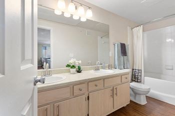 A bathroom with a large mirror and a toilet next to a bathtub